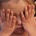 young child covering eyes